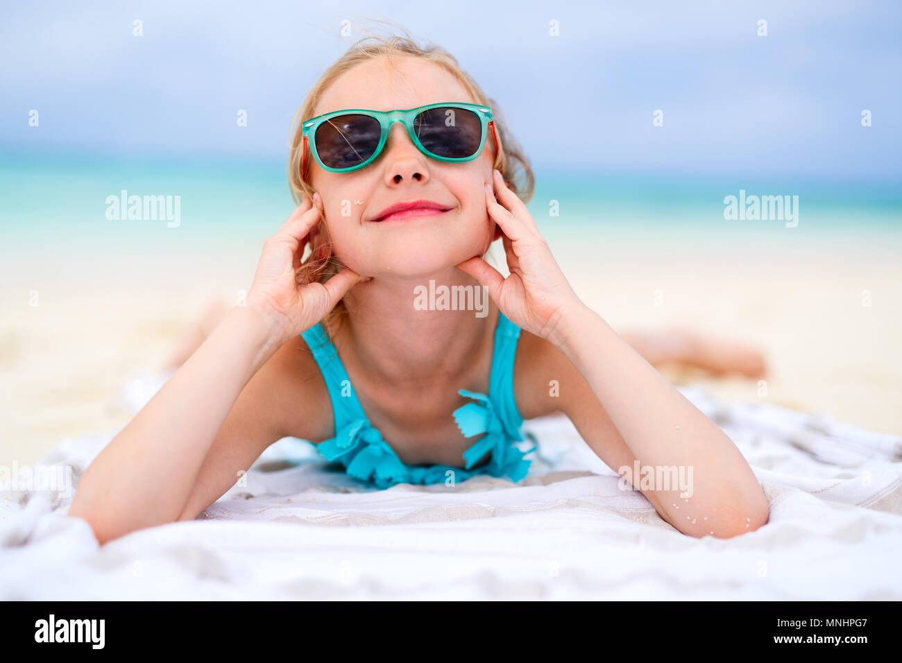 Adorable little girl lying on a beach towel during summer vacation