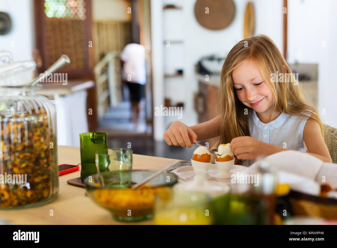 Adorable little girl eating boiled egg for a breakfast in restaurant