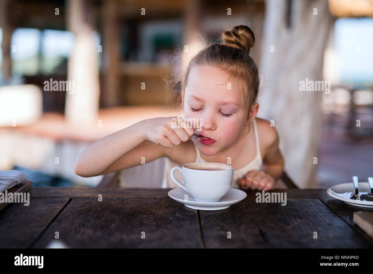 Adorable little girl in restaurant drinking hot chocolate Stock Photo