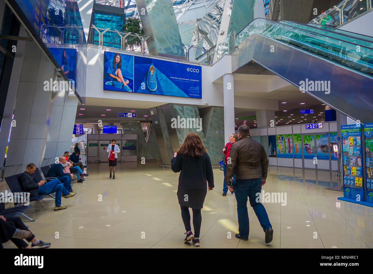 MINSK, BELARUS - MAY 01 2018: Travelers in a waiting room, inside of the  international airport of Minsk with a screen of departures and arrivarls  for their flight Stock Photo - Alamy