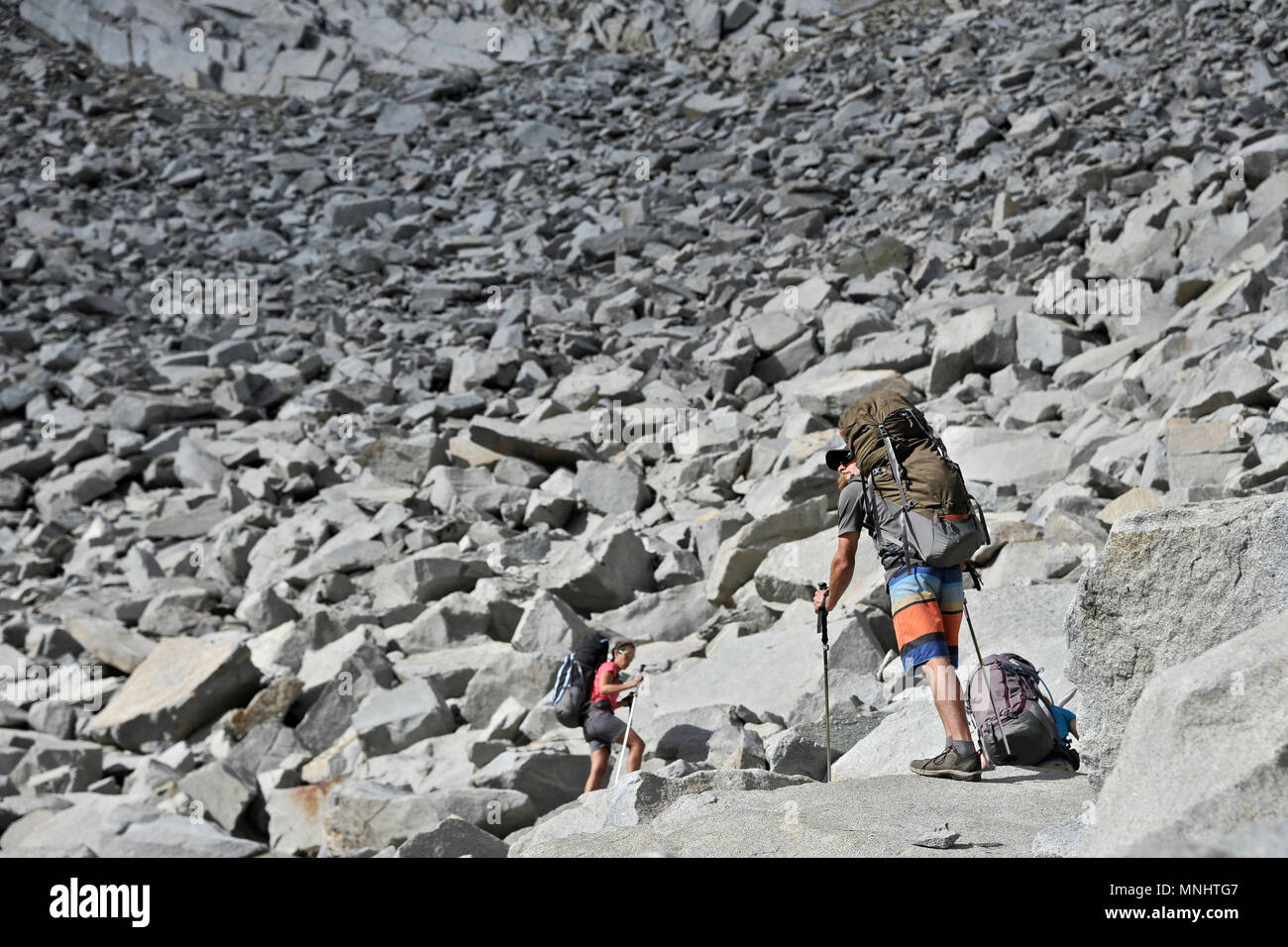 Backpackers climb through steep talus to Frozen Lake Pass on a two-week trek of the Sierra High Route in Kings Canyon National Park in California. The 200-mile route roughly parallels the popular John Muir Trail through the Sierra Nevada Range of California from Kings Canyon National Park to Yosemite National Park. Stock Photo
