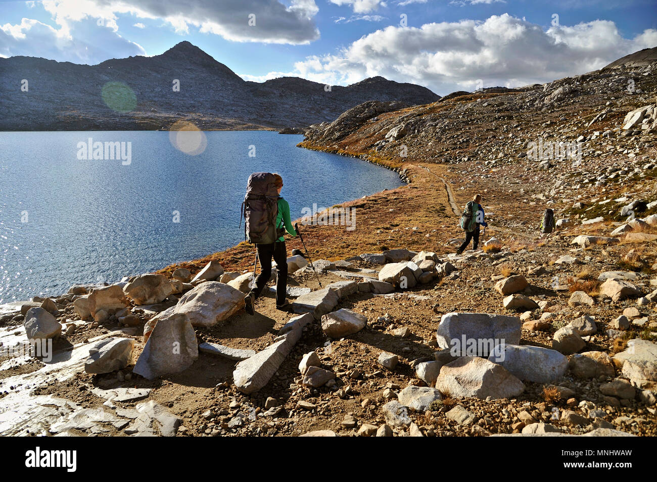 Backpackers hike the John Muir Trail through past Wanda Lake in the Evolution Basin on a two-week trek of the Sierra High Route in Kings Canyon National Park in California. The 200-mile route roughly parallels the popular John Muir Trail through the Sierra Nevada Range of California from Kings Canyon National Park to Yosemite National Park. Stock Photo