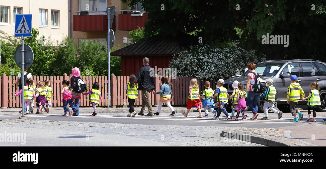 Landskrona, Sweden - May 31, 2013: Kindergartens children in Sweden dressed in fluorescent vests crossing the street at a pedestrian crossing with the Stock Photo