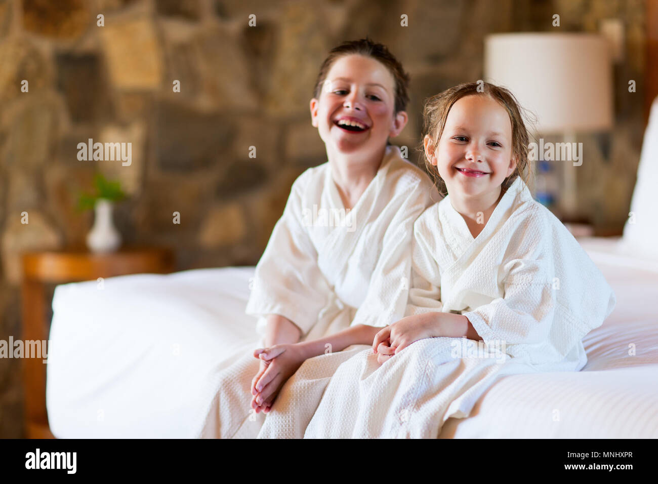 Two kids brother and sister wearing little bathrobes laughing while