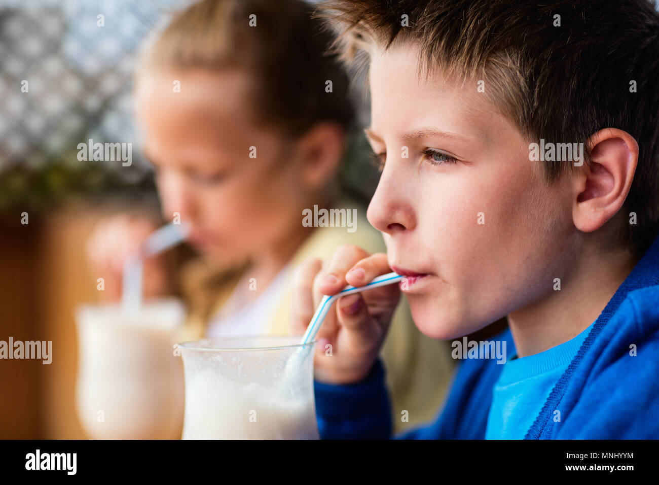 Kids brother and sister drinking milkshakes in outdoor cafe Stock Photo