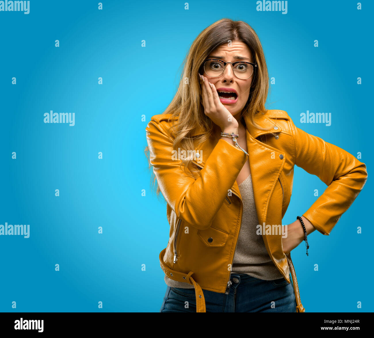 Beautiful young woman scared in shock, expressing panic and fear, blue ...