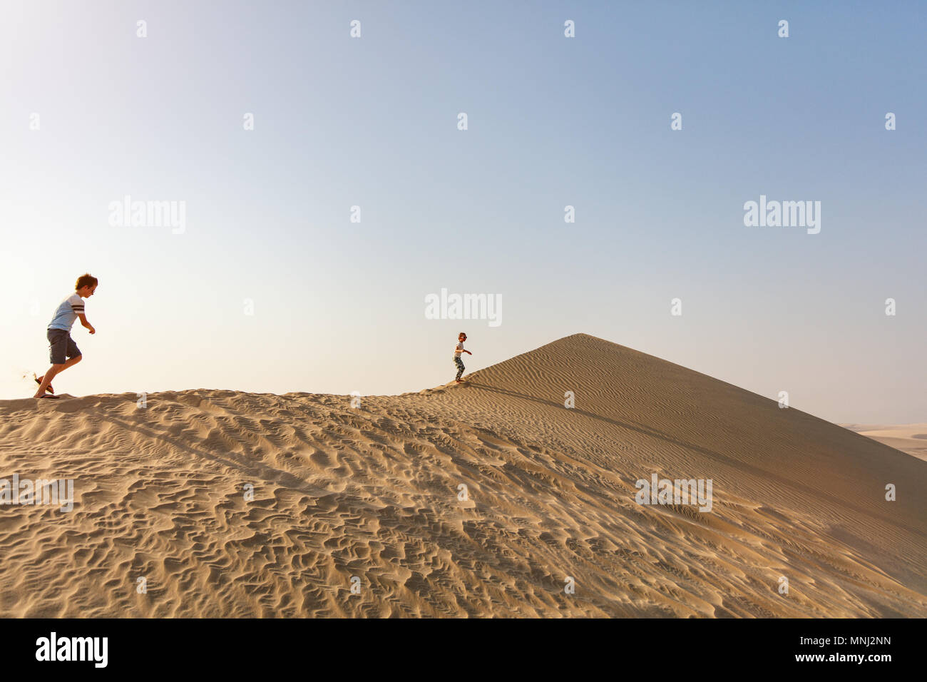 Kids having fun playing together at sand dunes in Qatar desert Stock ...