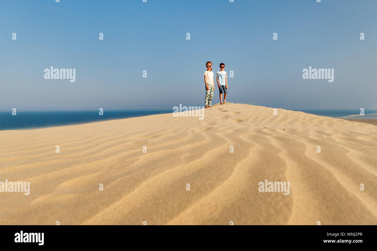 Kids having fun playing together at sand dunes in Qatar desert Stock ...