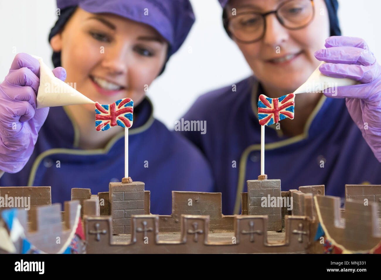 Chocolatiers pipe the finishing touches onto the front of Windsor Castle at Cadbury World in Birmingham, which is made entirely out of chocolate and includes the Henry VIII gate with a hand-piped picture of St George's Chapel visible through it, ahead of the royal wedding this weekend. Stock Photo