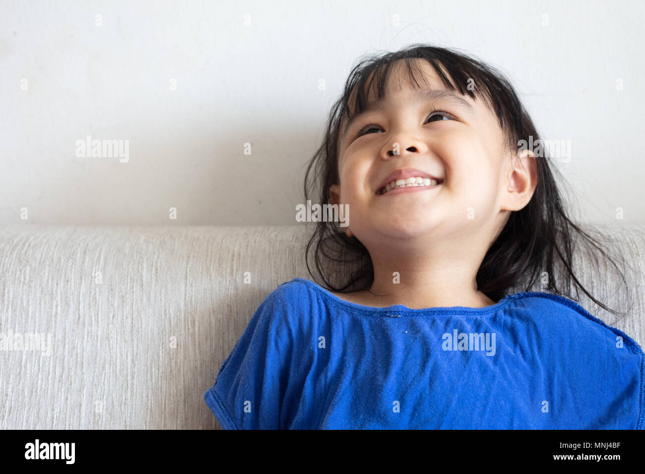 Asian Chinese little girl sitting on the sofa in the living room at ...