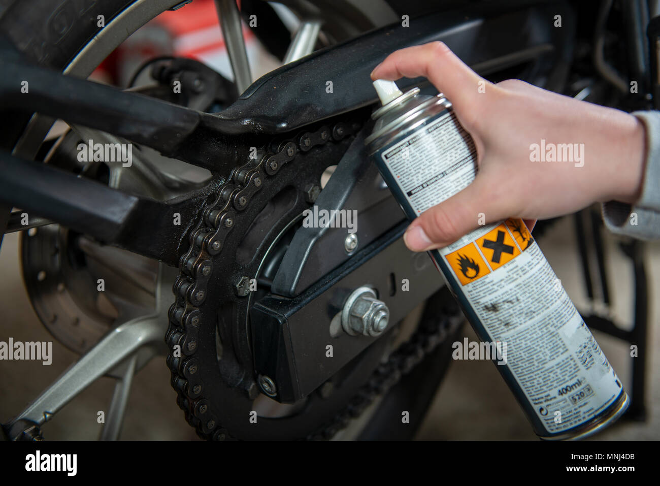 a lubricating motorcycle chain with chain spray grease Stock Photo Alamy