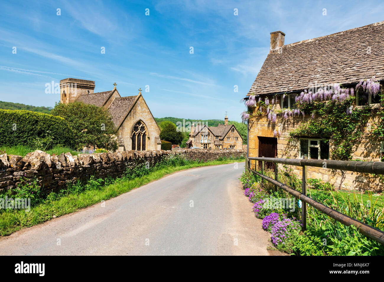 Snowshill, Cotswolds, England, UK. Wisteria flowers on a cottage next to the church in a Cotswold village. Stock Photo