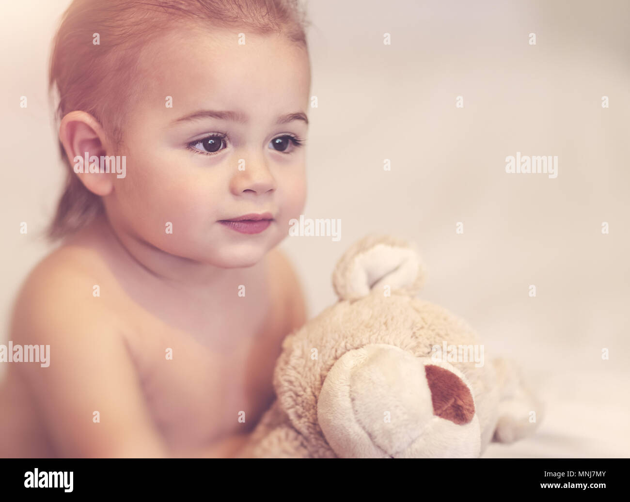 Portrait of a cute little boy with soft bear toy at home, woke up after ...