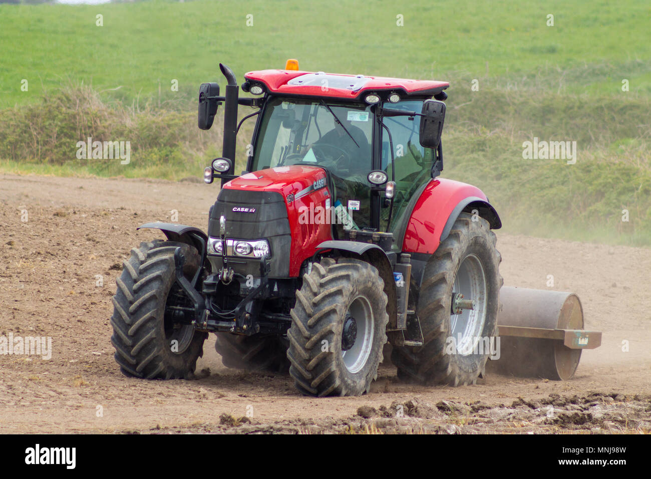 farmer rolling a field on a farm in ireland, with a heavy roller pulled