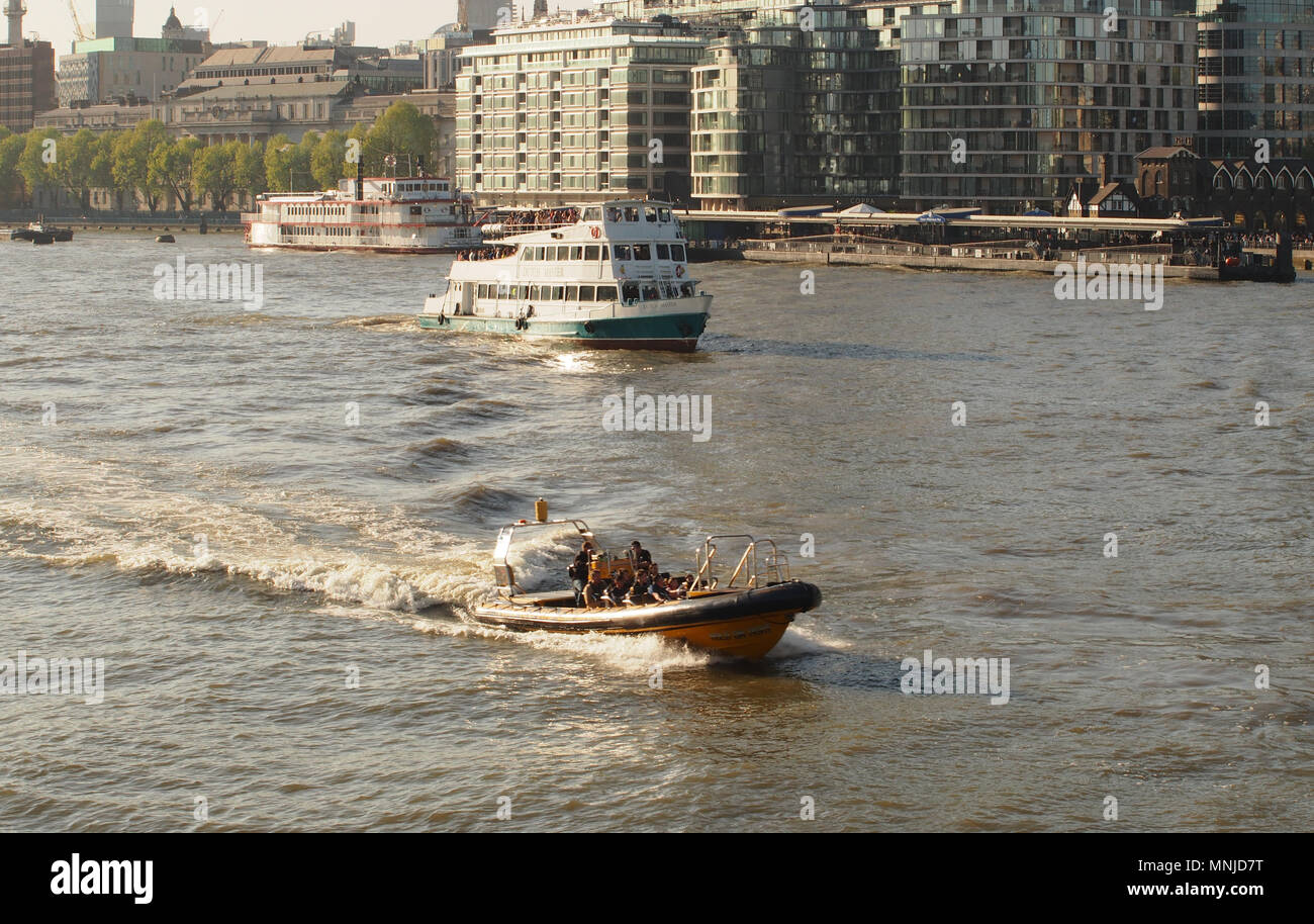 Three different types of river craft on the River Thames near Tower Bridge, London. A motor boat, paddle steamer and passenger ferry and buildings Stock Photo