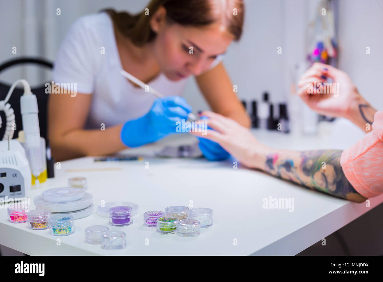 Manicurist treating client at beauty salon - painting on the nai Stock Photo