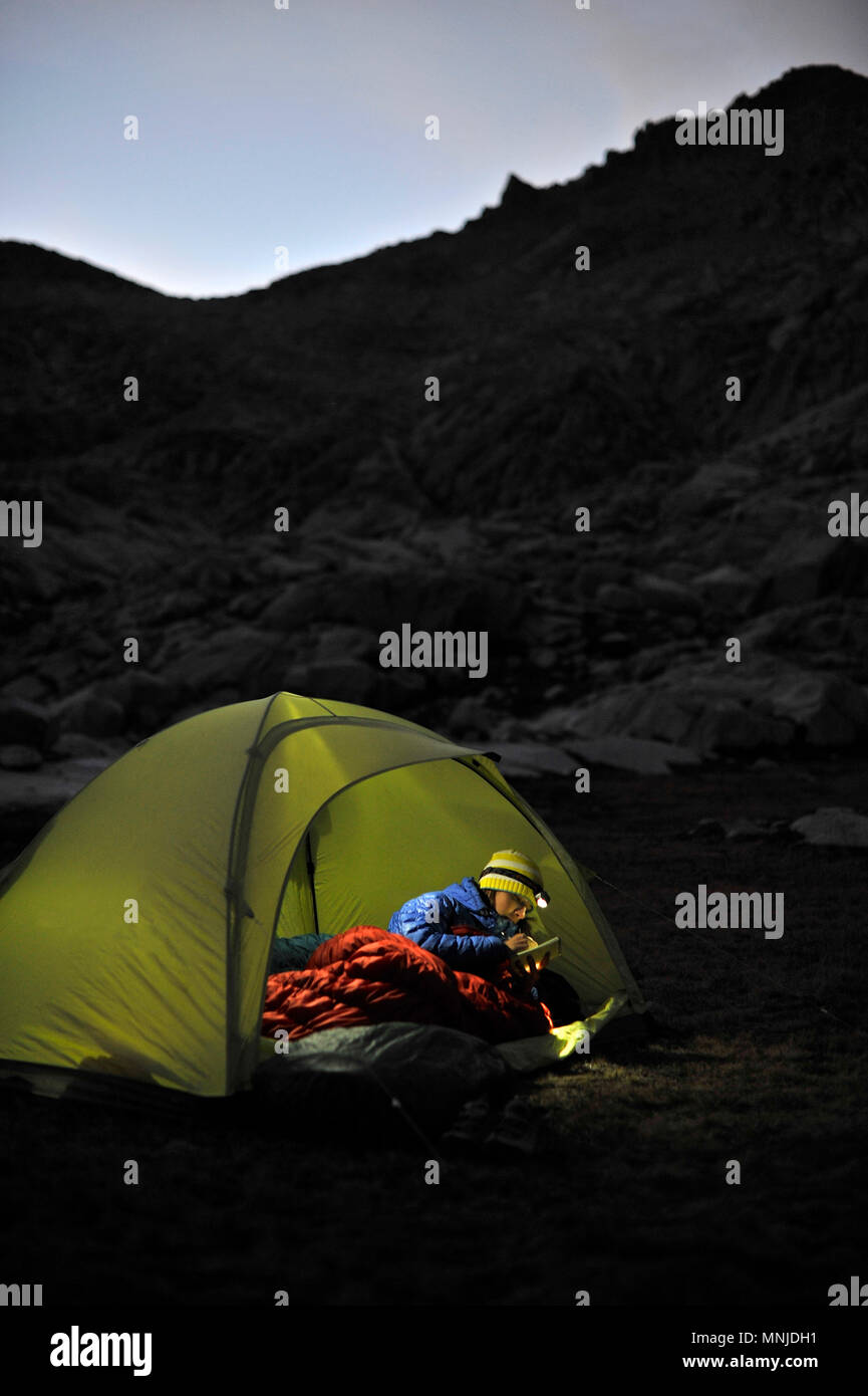 Backpacker uses a headlamp at camp on Blue Lake while on a two-week trek of the Sierra High Route in the Ansel Adams, Inyo National Forest, California. The 200-mile route roughly parallels the popular John Muir Trail through the Sierra Nevada Range of California from Kings Canyon National Park to Yosemite National Park. Stock Photo