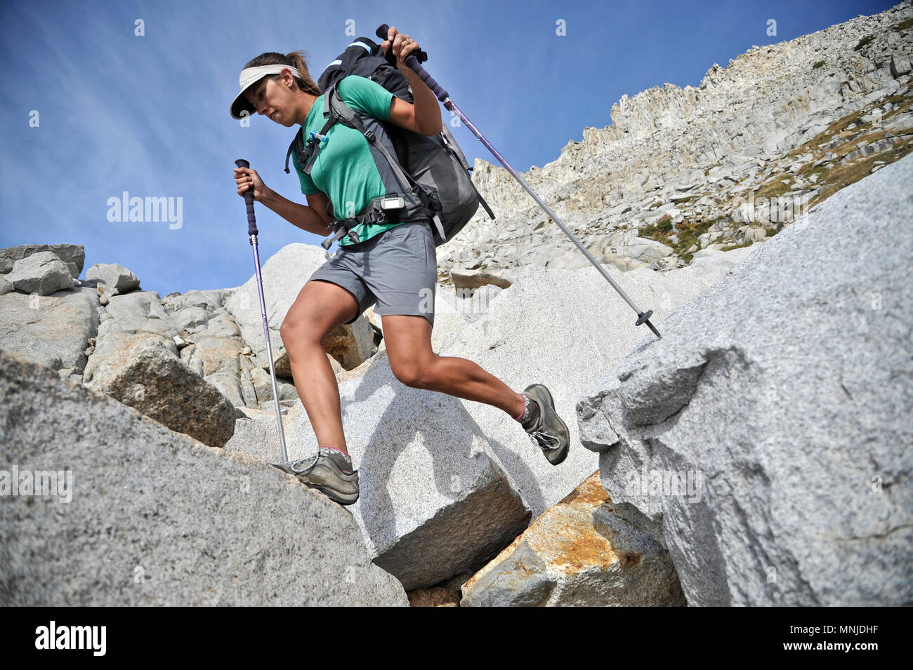 Backpacker uses trekking poles on her scramble to Blue Lake Pass while on a two-week trek of the Sierra High Route in the Ansel Adams, Inyo National Forest, California. The 200-mile route roughly parallels the popular John Muir Trail through the Sierra Nevada Range of California from Kings Canyon National Park to Yosemite National Park. Stock Photo