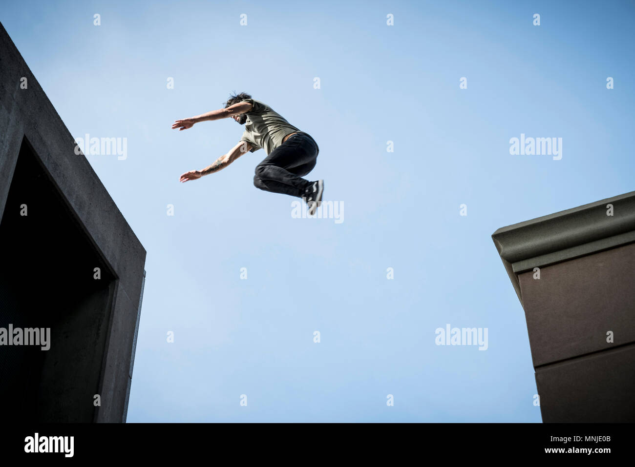 Local park athlete jumping across rooftops in downtown Denver, Colorado, USA Stock Photo