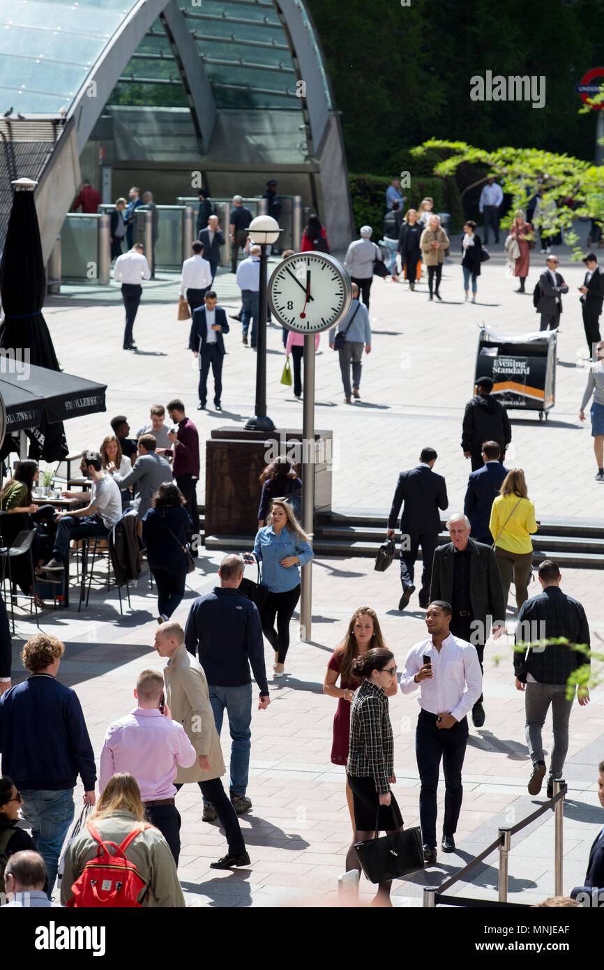 The glass arch entrance to Canary Wharf tube station, with professionals in the foreground heading to and from work, or on their lunch breaks. Stock Photo