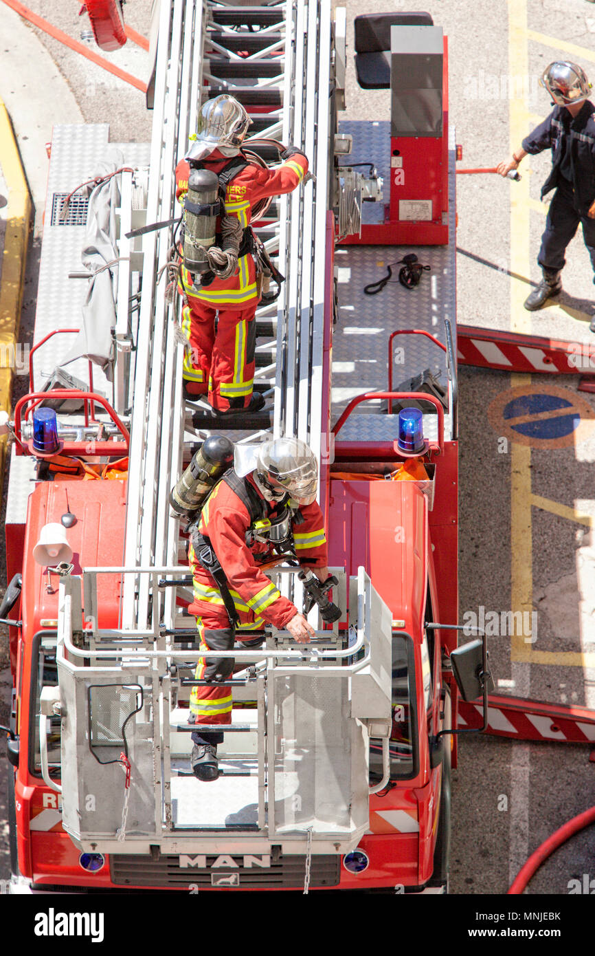 High angle view of two firefighters standing on fire engine turntable ladder during intervention, Marseille, Bouches-du-Rhone, France Stock Photo