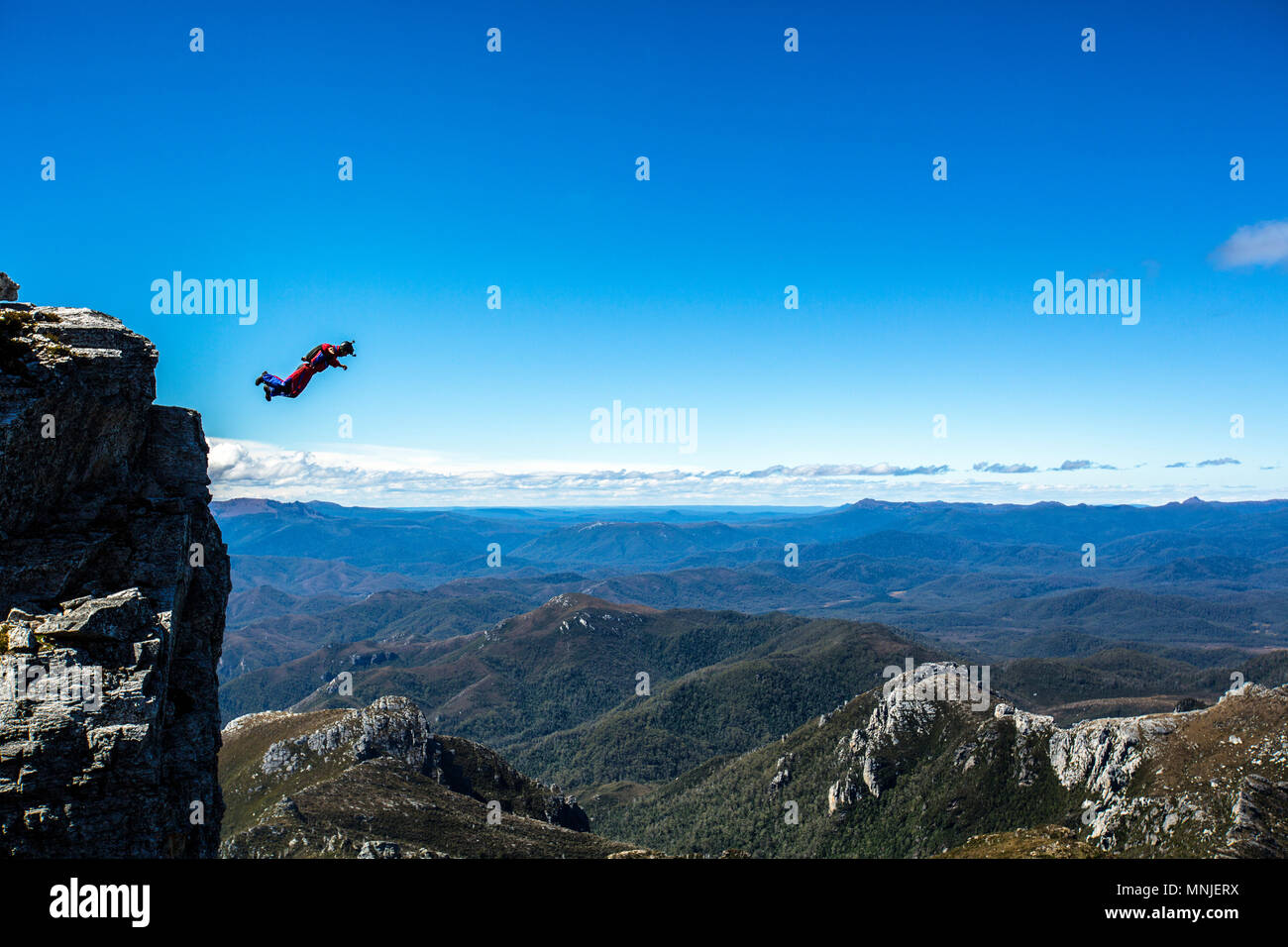BASE jumper during free fall against clear blue sky right after jumping off from top of Frenchman's Cap, Tasmania, Australia Stock Photo