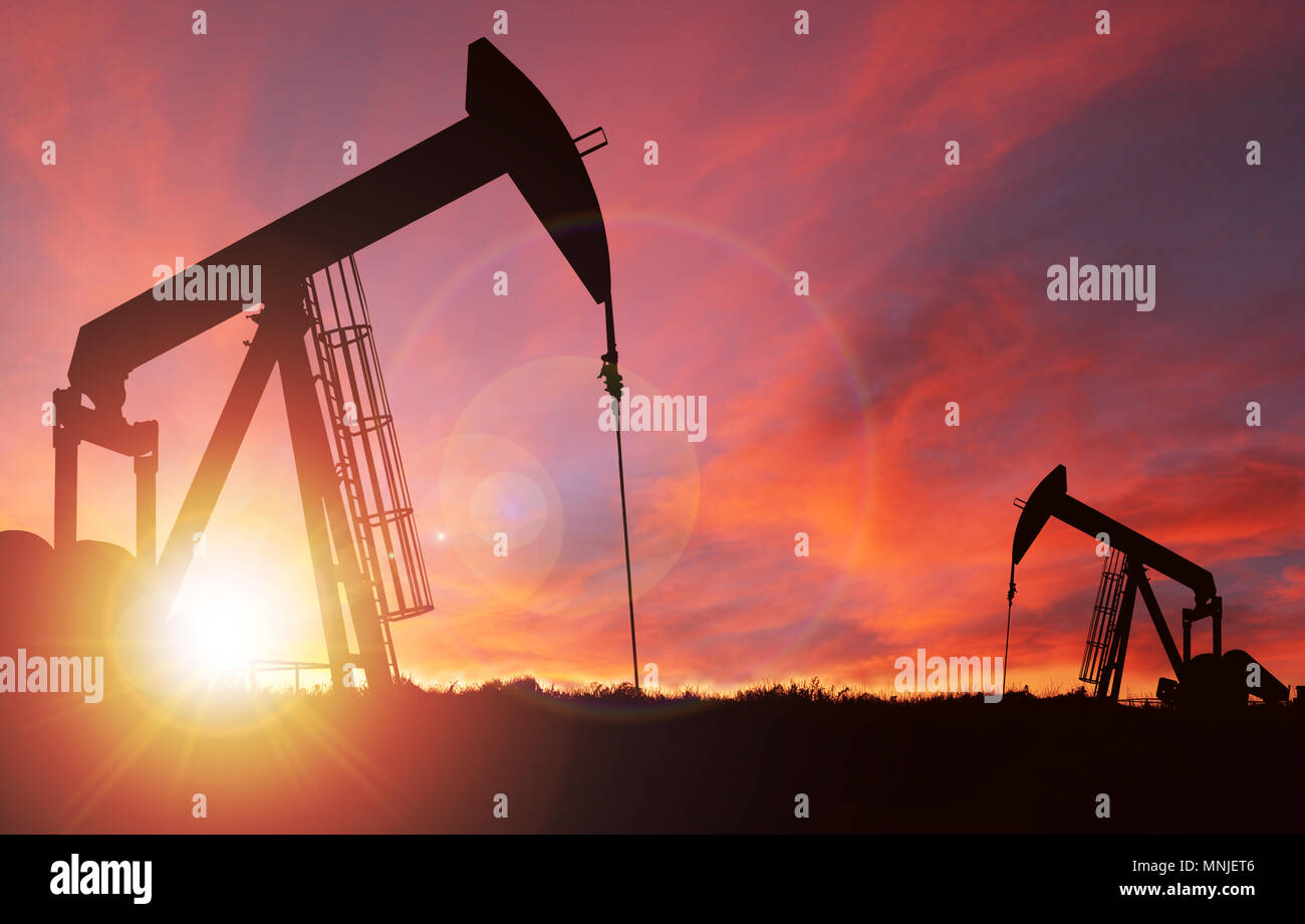 Pump jack silhouette against a sunset sky with deliberate lens flare and copy space. These jacks can extract between 5 to 40 litres of crude oil and w Stock Photo