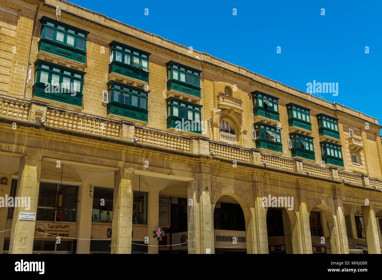 Valletta, Malta Freedom Square building. Day view of traditional Maltese limestone building with green balconies and shops at top of Republic Street. Stock Photo