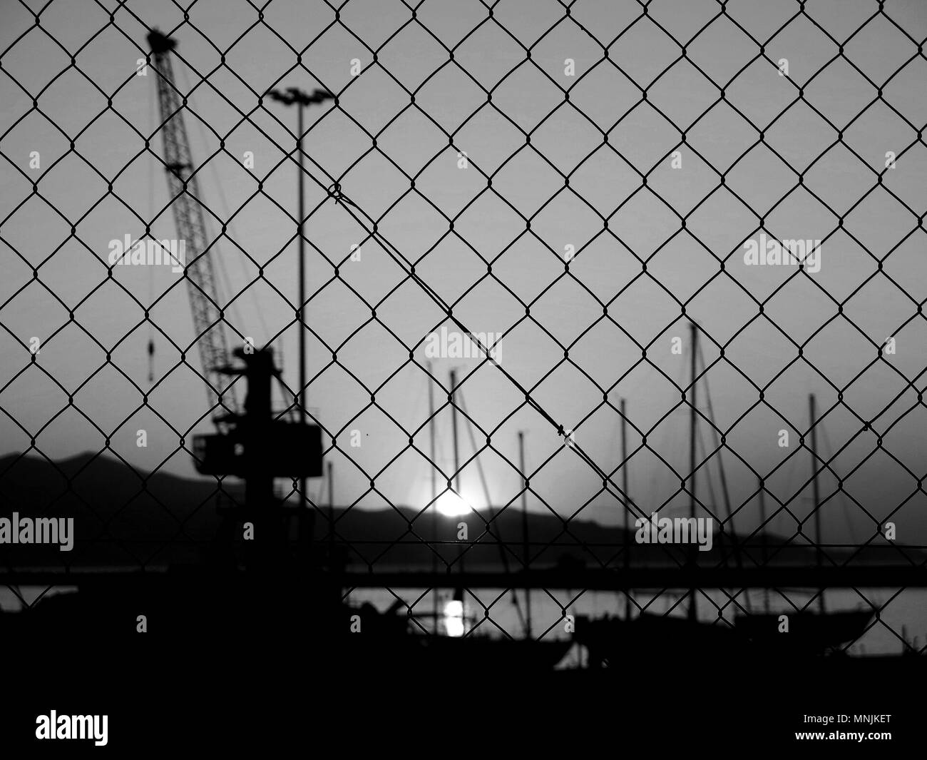 Boat yard seen through metallic fence during sunset. Stock Photo