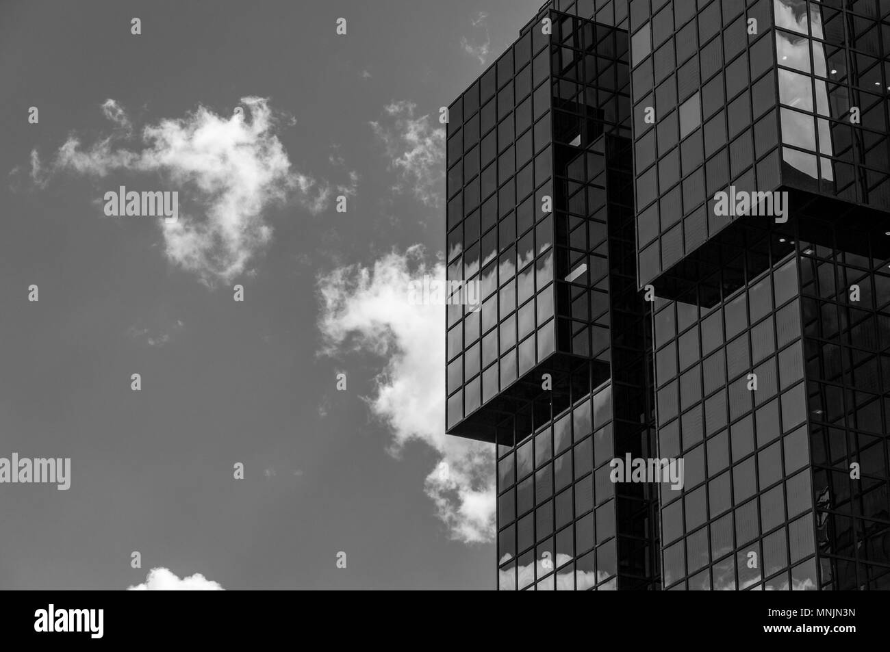 Black and white image looking up at a cloud reflected in a modern office building in London Stock Photo
