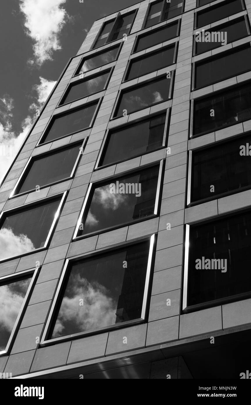 Black and white image looking up at a modern office building with reflections in the windows Stock Photo