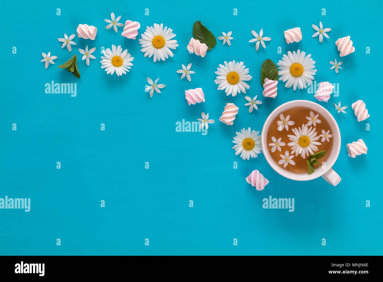 Cup of tea with marshmallows and flowers blossom bouquets on blue