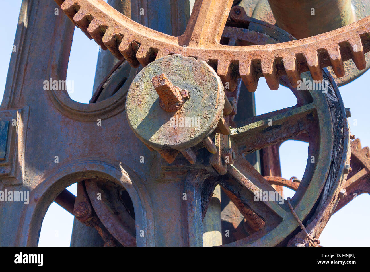 cast iron gantry crane with wooden jib or boom showing the original hand turned cast iron gearing, gear wheels, gear teeth, cogs and drive shaft. Stock Photo