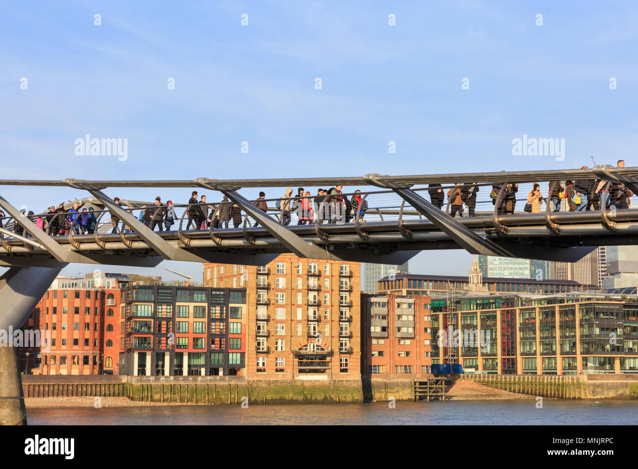 People walking across the Millennium Bridge above the River Thames on a beautiful sunny day, London, England, UK Stock Photo