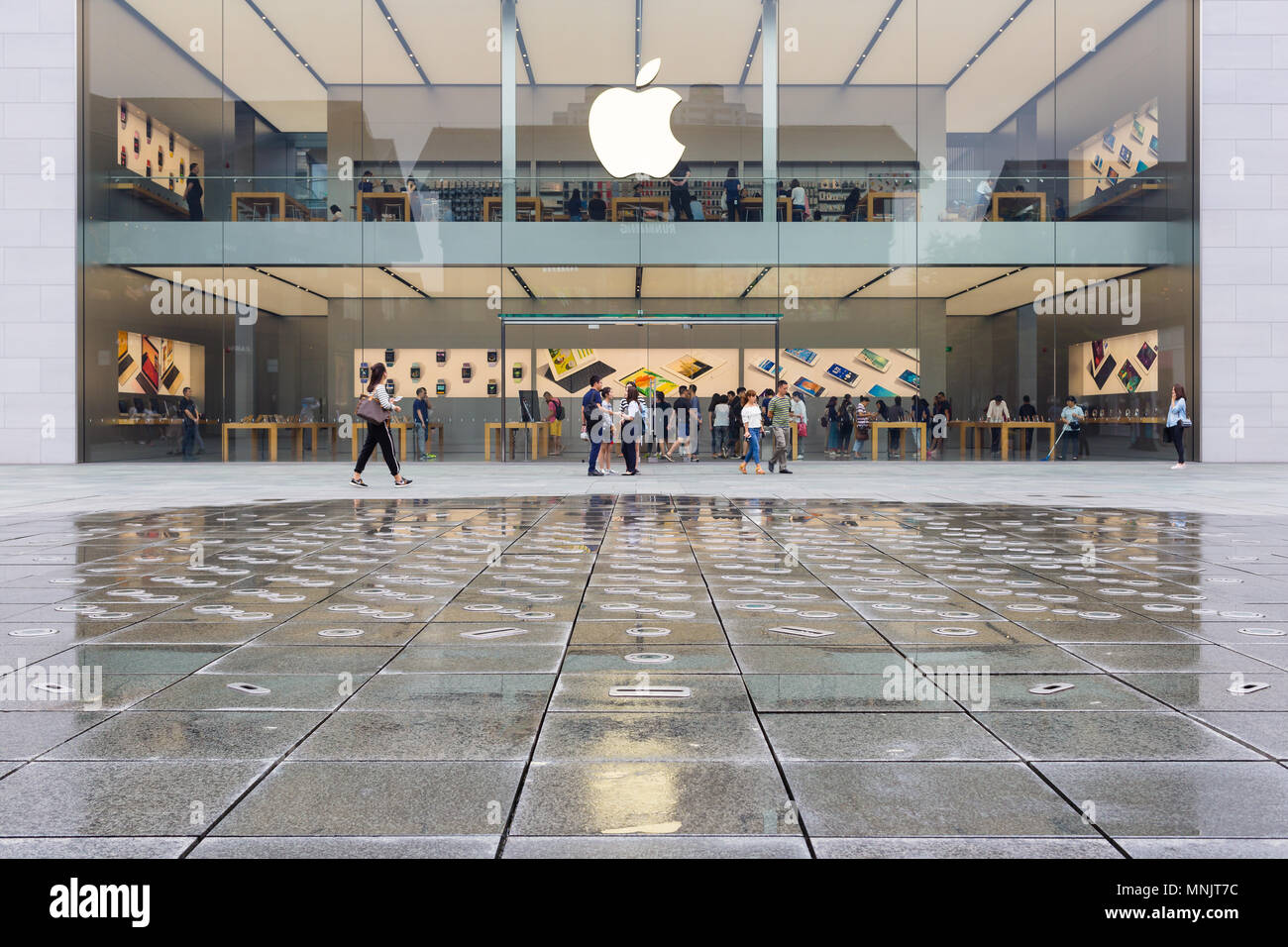 CHENGDU , CHINA - SEPTEMBER 13, 2016: Apple Store in Chengdu , China , with pedestrians passing by outside the store during a rainy day . Stock Photo