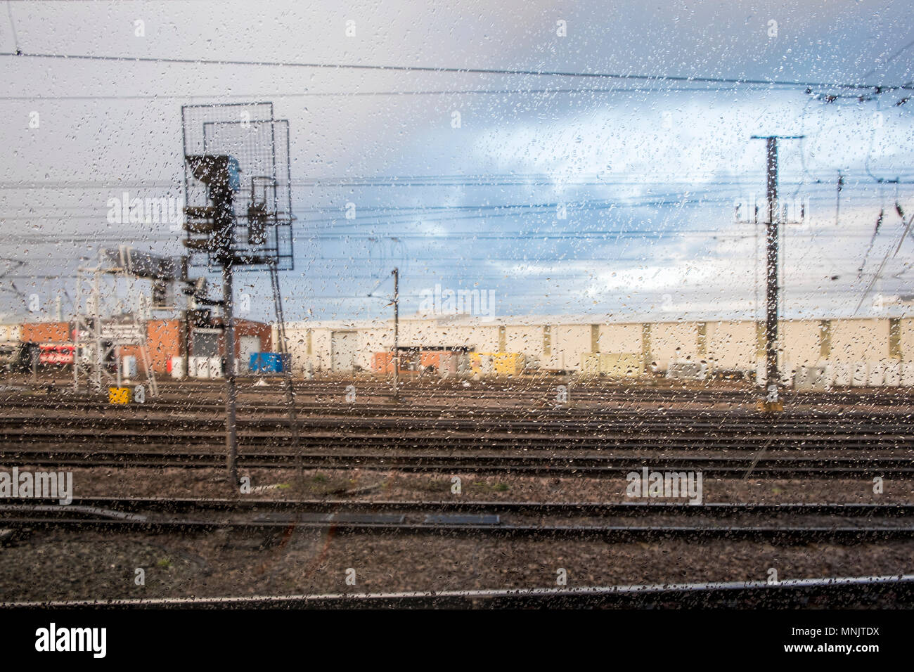 Wet weather. Looking out through a train window with rain drops on the glass at railway tracks on a rainy day, Doncaster, England, UK Stock Photo