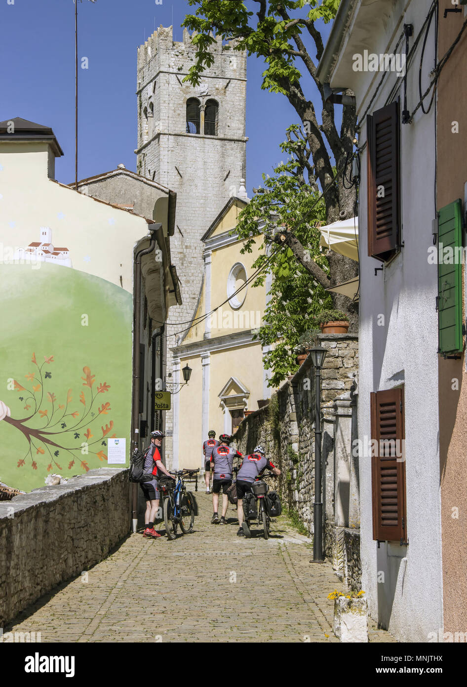 Central Istria, Croatia, April 2018 - Cyclists pushing their bicycles down the narrow cobbled street in the ancient town of Motovun Stock Photo