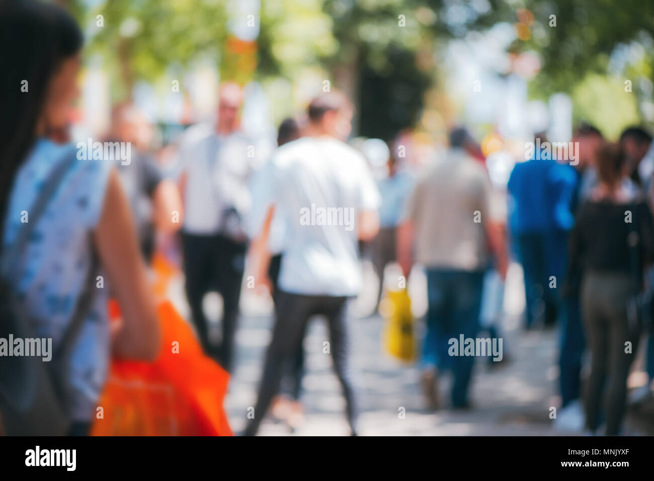 Abstract blurry background, people walking on crowded street on sunny summer day. Defocus blurred background as graphic design element. Stock Photo