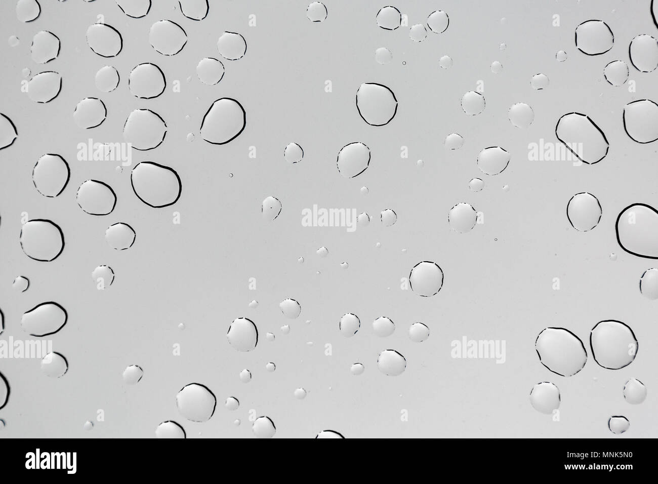 Rain drops on window glasses surface with cloudy background Stock Photo