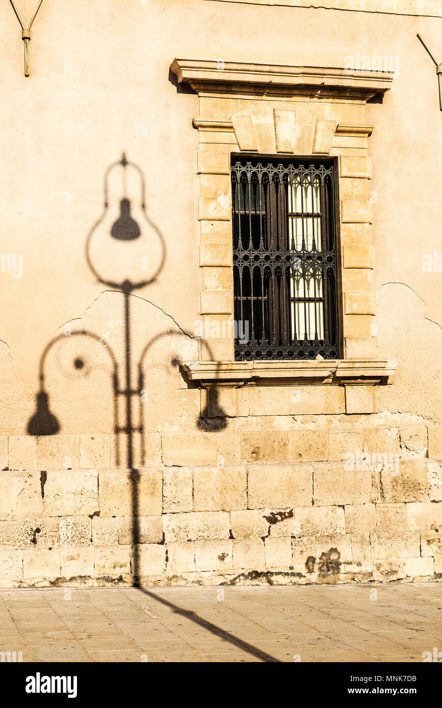 Shadow of a classic black lamppost on a building in Piazza Duomo in the old town of the historic city of Siracusa in Sicily, Italy Stock Photo