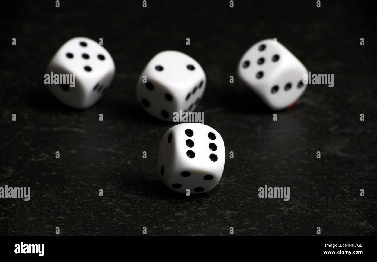 Four white and black dice on a black table Stock Photo