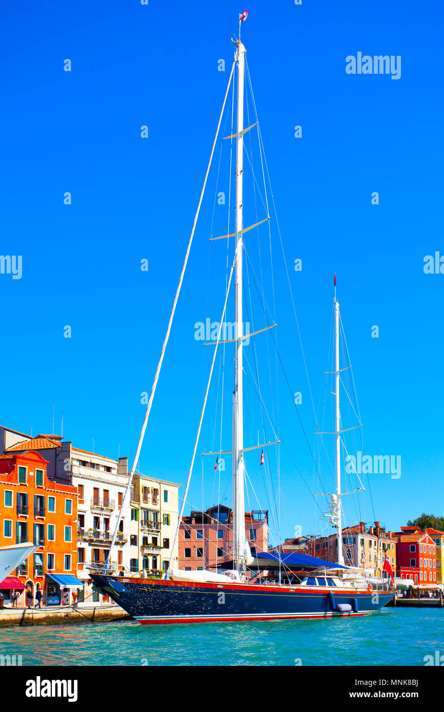 Waterfront in Venice and moored sail yacht with tall masts, Italy Stock Photo