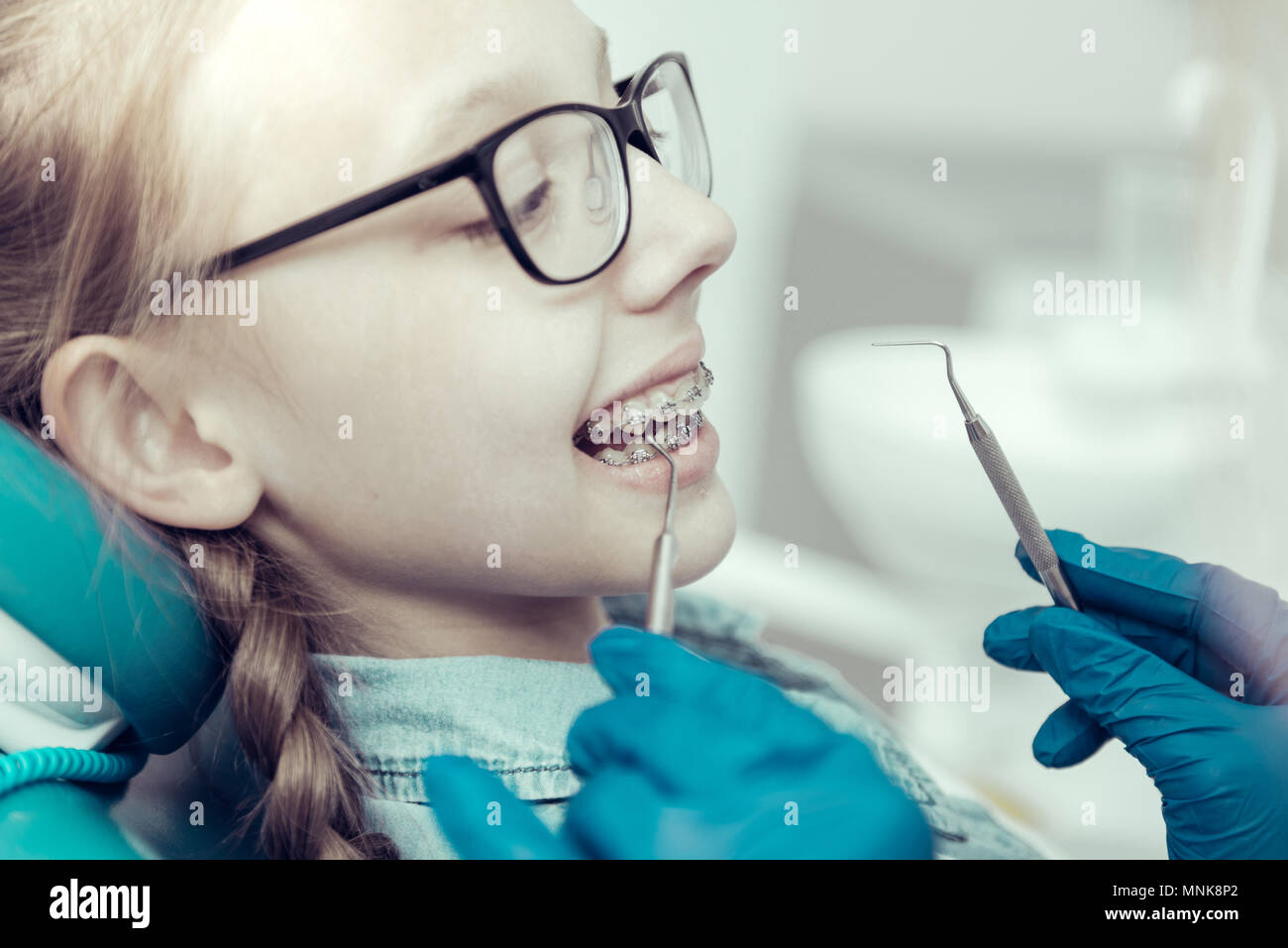 Little girl in braces sitting in a dental chair Stock Photo