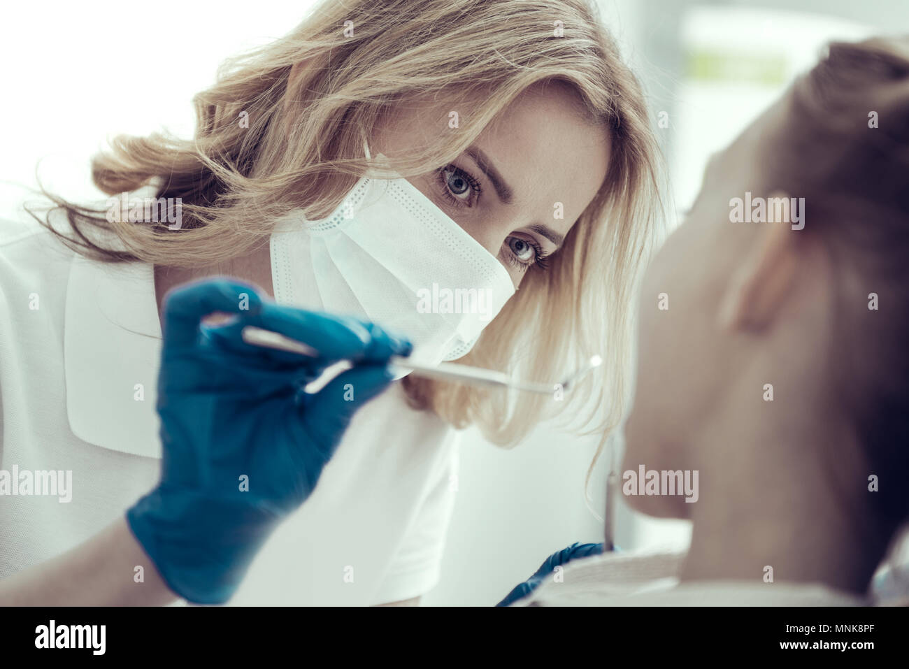 Diligent dentist holding a dental mirror during the examination Stock
