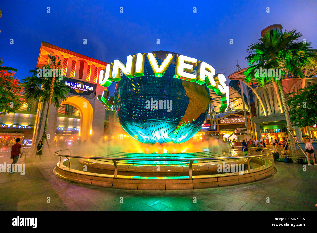 Singapore - May 2, 2018: Universal Studios world globe in green light, with tourists visiting this Hollywood movie theme park in Sentosa island. Stock Photo