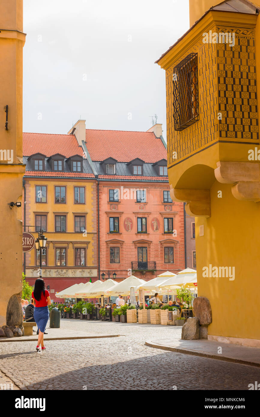 Warsaw Old Town, a young woman enters the colourful Old Town Square in the historic Stare Miasto quarter of Warsaw, Poland. Stock Photo
