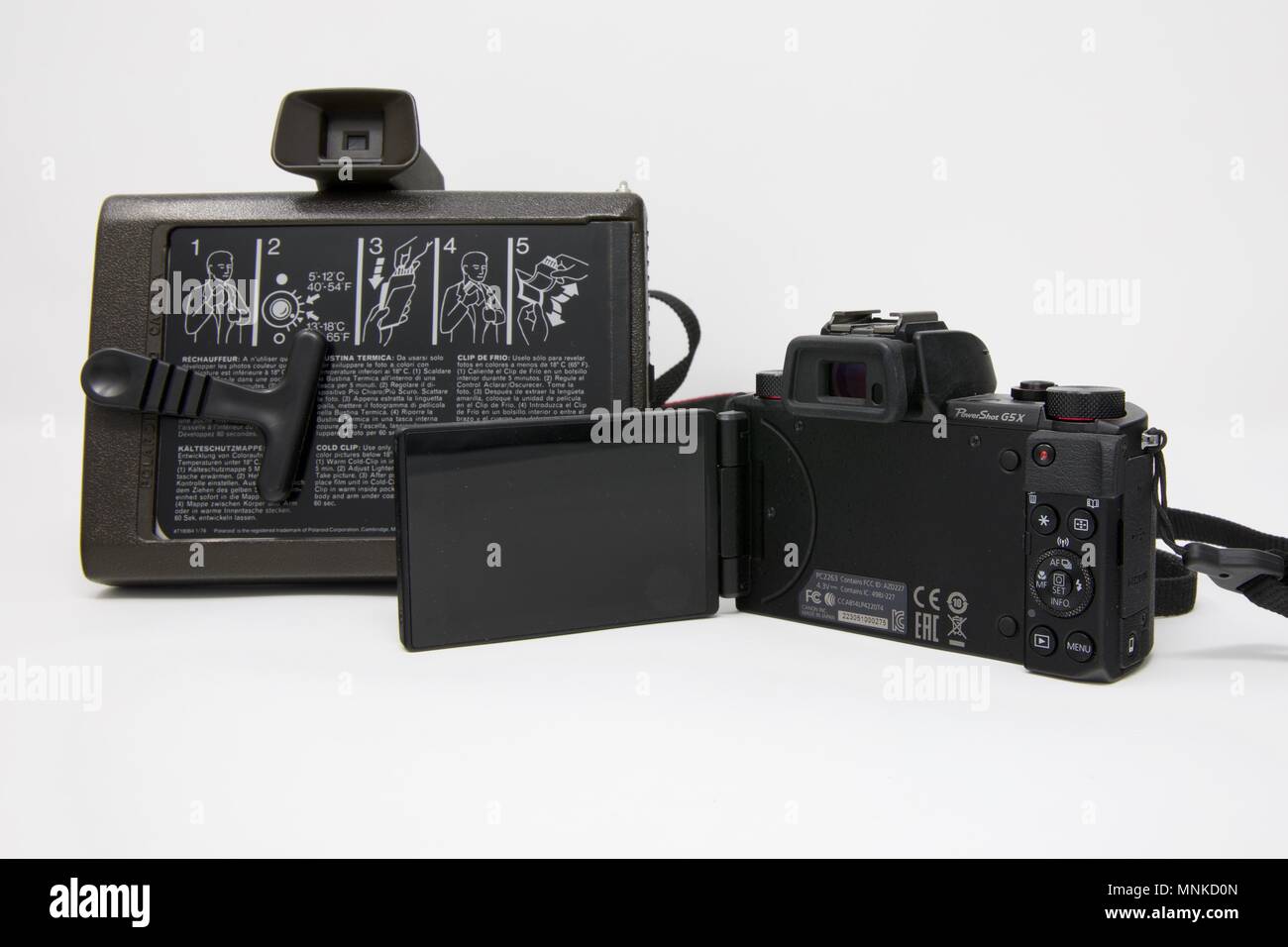 1975 Polaroid Colour Swinger Camera next to a modern Canon PowerShot G5 X Camera Stock Photo