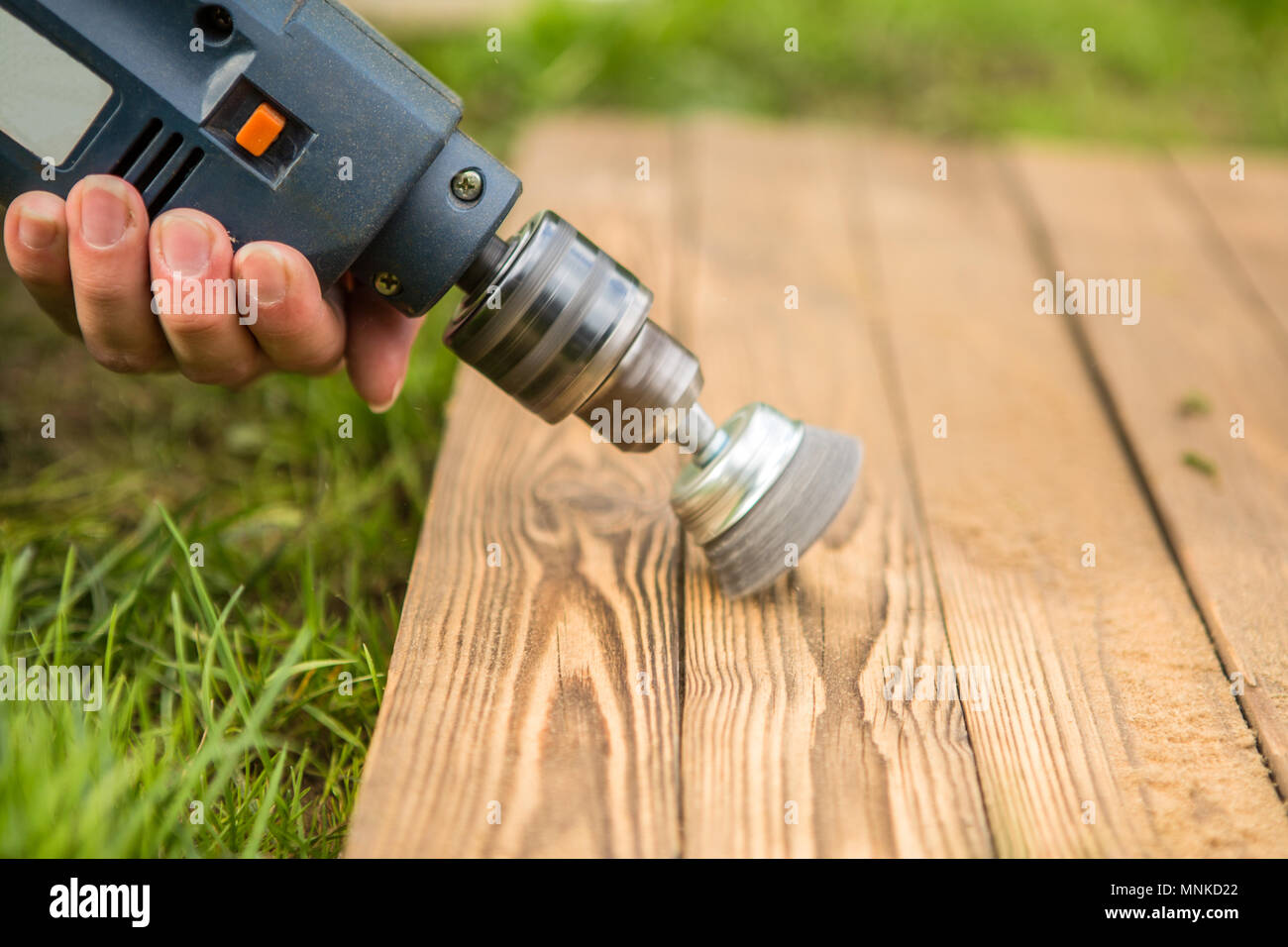 Hands man with electrical rotating brush metal disk sanding a piece of