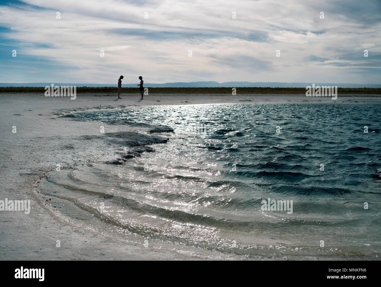 Silhouette of a couple talking in the background of Laguna Cejar, Chile. Stock Photo