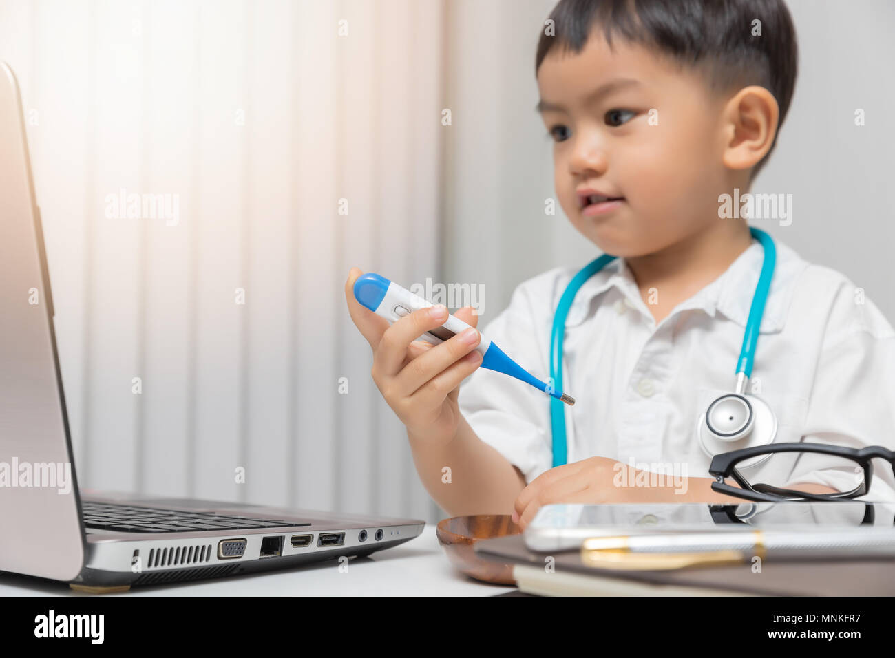 Young asian boy playing doctor and holding a thermometer. Stock Photo